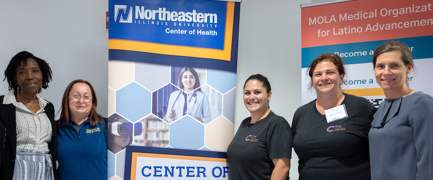 A group photo of Northeastern ChicagoCHEC collaborators in front of a banner with the text "Northeastern Illinois University Center of Health."
