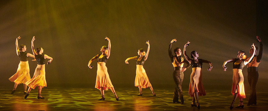 Ensemble Español performing "Sur." Dancers are wearing black and yellow costumes and are covered in yellow/green stage light. Photo by Dean Paul/Courtesy of Ensemble Español.