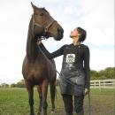 Kim Ambriz standing outdoors next to a brown horse