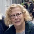 Woman with curly blond hair and dark glasses