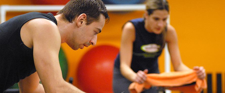 Two students working out on cycles in the gym