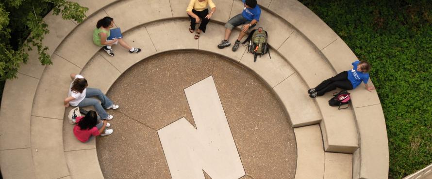 Students sitting in a rotunda outside. The NEIU N is the middle of the rotunda