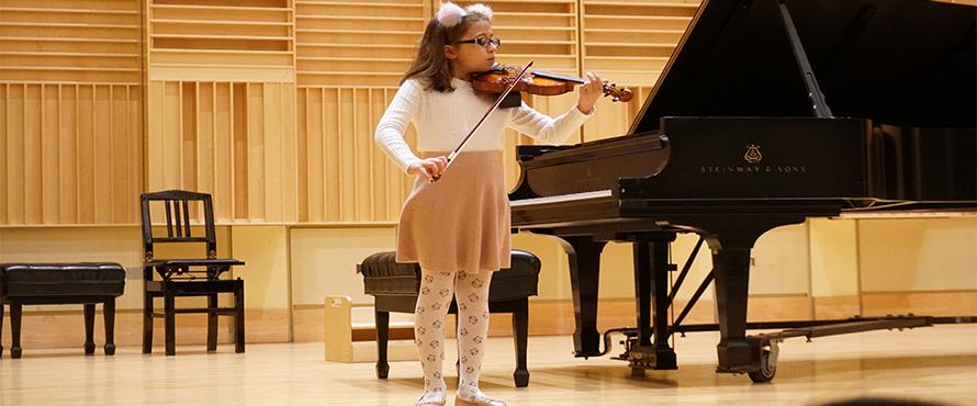 A student plays violin on the Recital Hall stage.