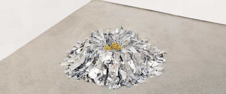 Metallic shimmerly sculpture with yellow center displayed on the floor