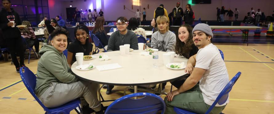 Students at a table enjoying food. 