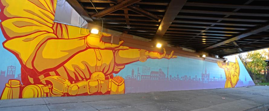 Photo of mural near El Centro showing hands holding up the train overpass