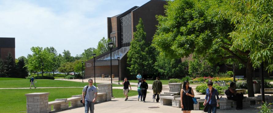 The University Commons at midday with male and female students walking the path between the library and Student Union