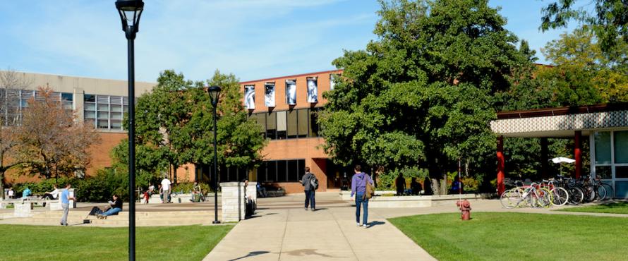 Partial view of the south side of the Fine Arts Building, Student Union and B Building with students walking and relaxing