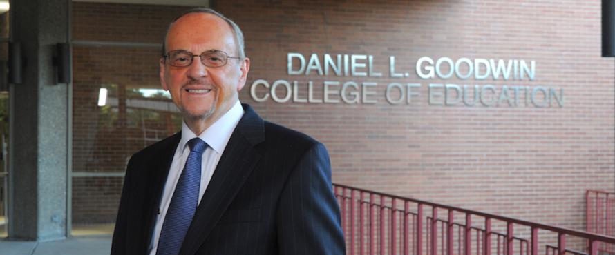 Daniel L. Goodwin stands outside of Lech Walesa Hall in front of a wall that reads Daniel L. Goodwin College of Education