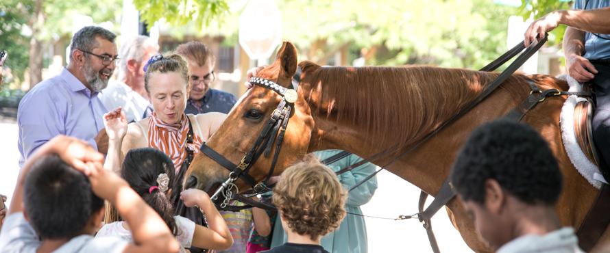 A photo of children in the STARTALK SAMI program petting a horse from the Chicago Police Department's Mounted Unit. 
