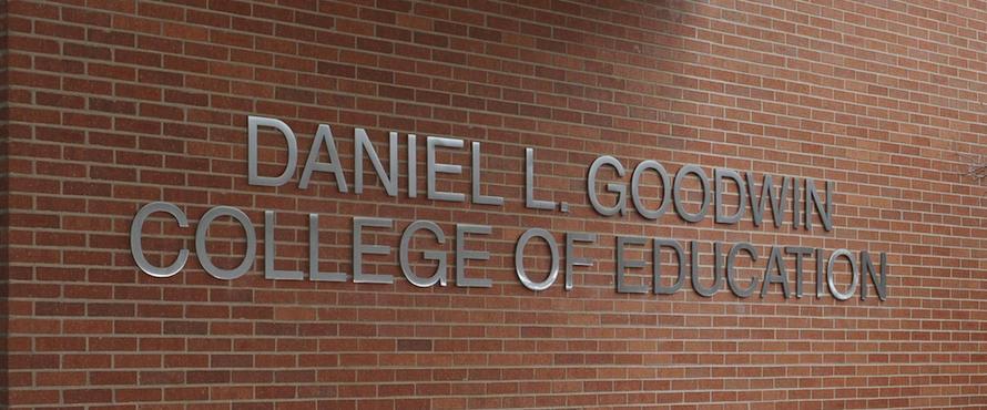 Photo of the exterior sign of the Daniel L. Goodwin College of Education in silver against brown brick