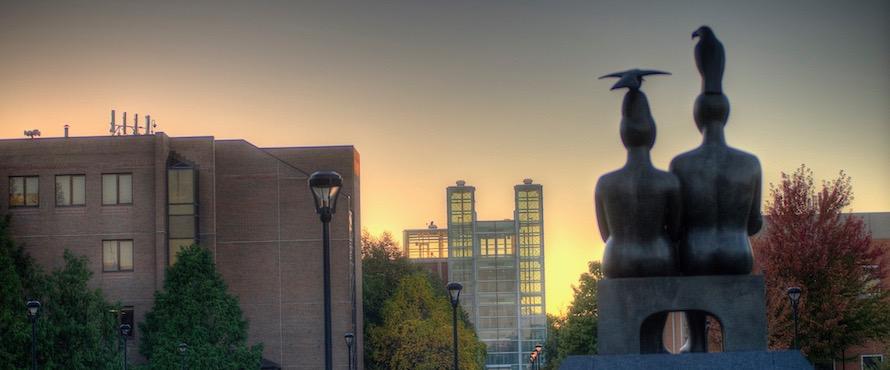 A statue is shown on campus at sunset.
