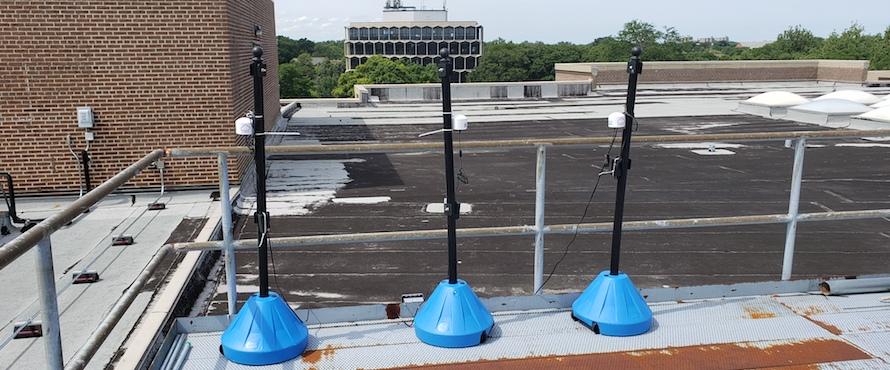 Photo of three PurpleAir sensors on the roof of Bernard Brommel Hall. 