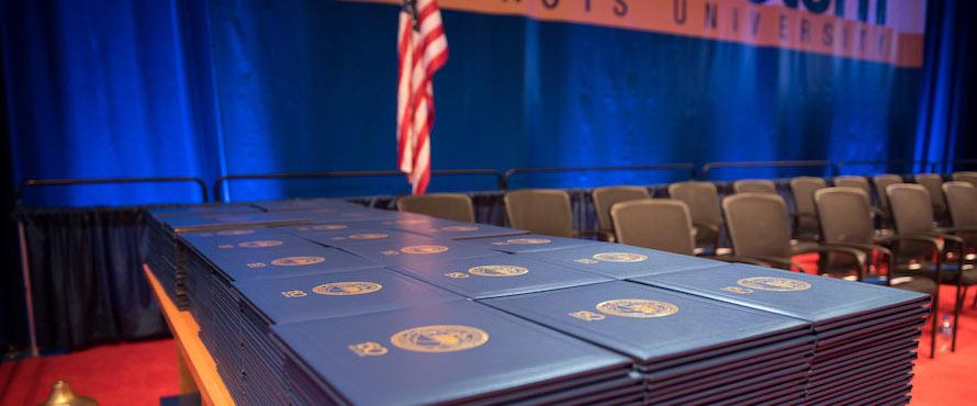 Diploma covers are stacked on a Commencement stage.