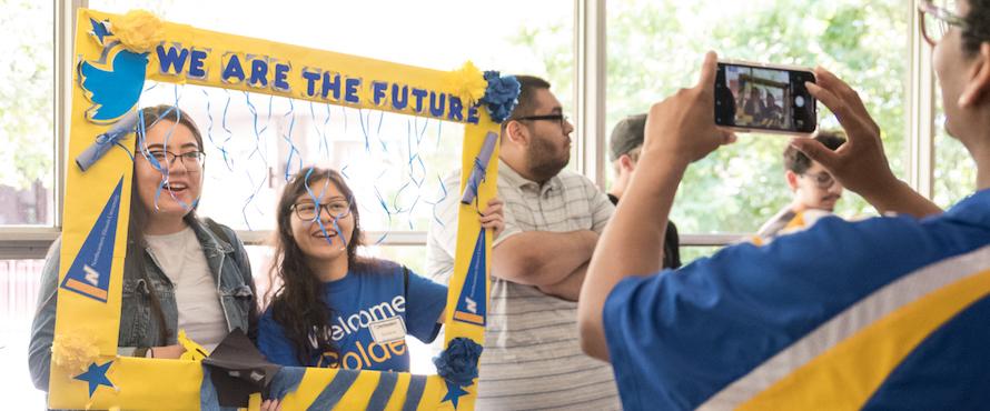 Photo of two students posing as a staff member takes a photo at NEIU Welcome Day 2021