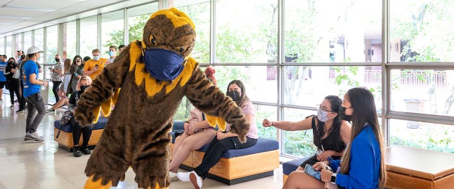 University mascot Goldie and a student fist bump during Golden Eagle Welcome Day