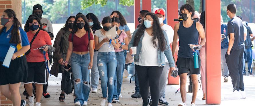 A group of students wearing face masks walk toward the camera