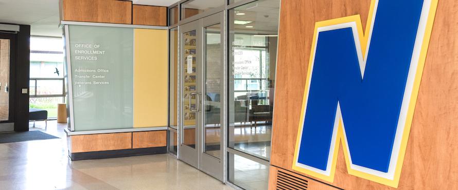 A photo of the exterior of the NEIU admissions office with the flying N logo on the wall