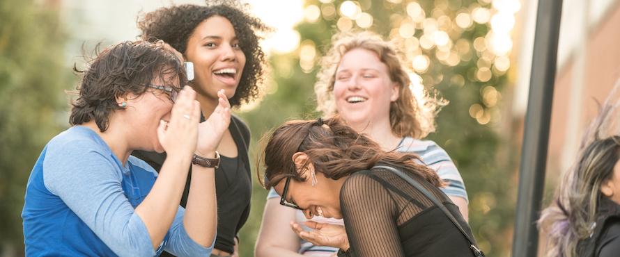 A photo of a group of four NEIU students laughing outside of the Main Campus