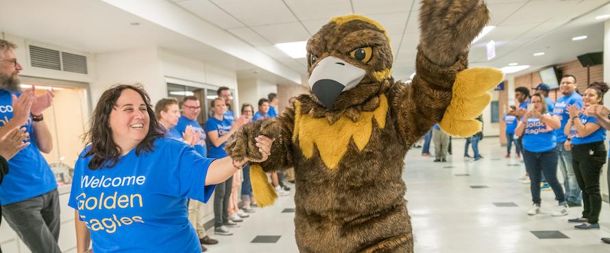 An NEIU employee and our Goldie mascot holding hands