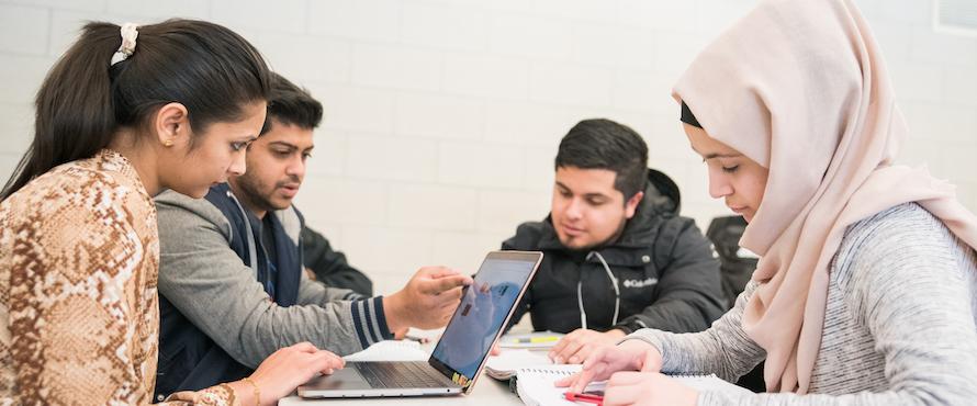 Photo of Northeastern students working on a project with a laptop computer and notebooks