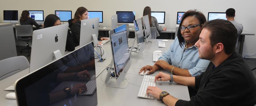 A photo of students sitting at computers in one of the labs at Northeastern's El Centro location.