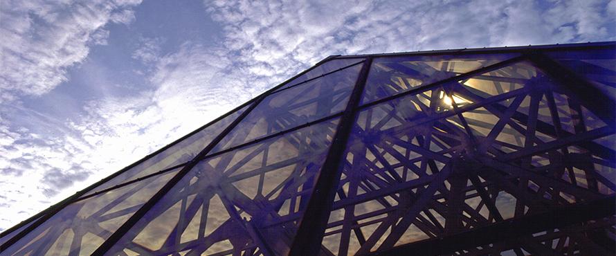 A glass roof is shown in front of a blue sky.