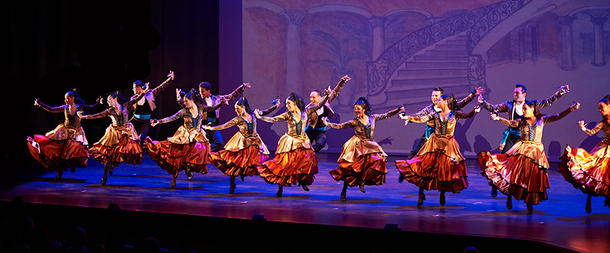 A line of Ensemble Español dancers performs on stage.