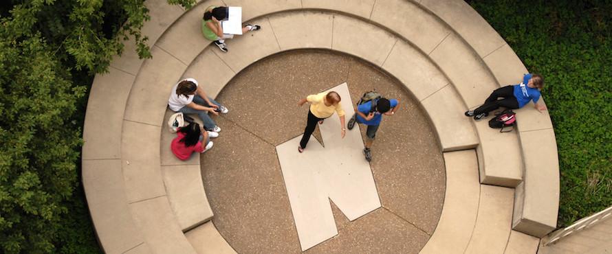 Seen from directly above, people sit and walk near a resting space that has the Flying N logo in the center 