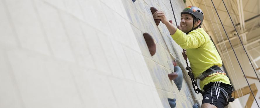 Student Climbs rock wall at the PE complex