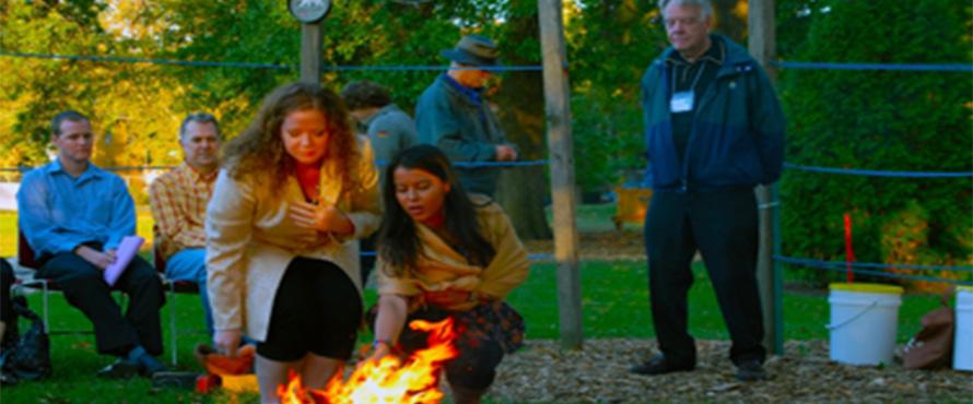 Individuals stand around a fire during the Art in Response to Violence Conference