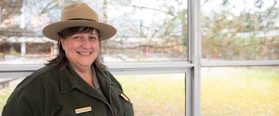 Kathleen Kelly smiles into the camera while wearing her park ranger uniform.