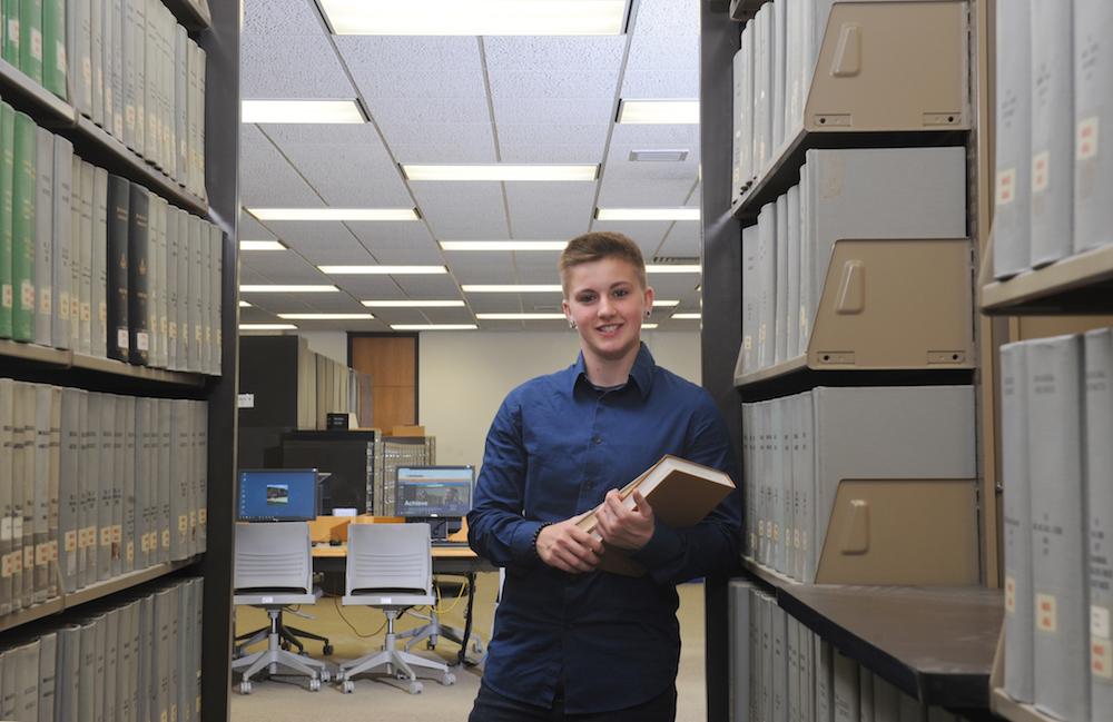 Becca Peterson holds two books in the library.