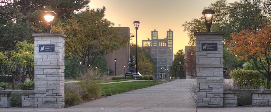 A photo of the entrance to NEIU's Main Campus from St. Louis Ave. with a view of the path runs across the University Commons to the Parking Facility, visible in the background.