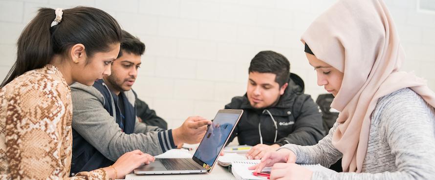 Four Northeastern students sitting at a table working on a project with a computer