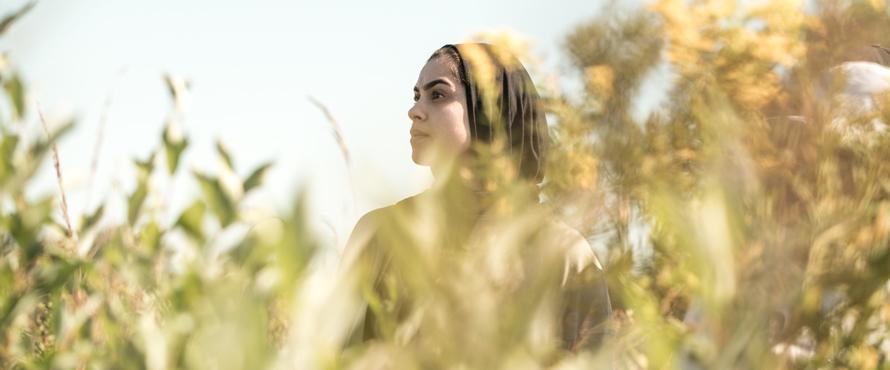 A woman's face is framed by tree leaves.