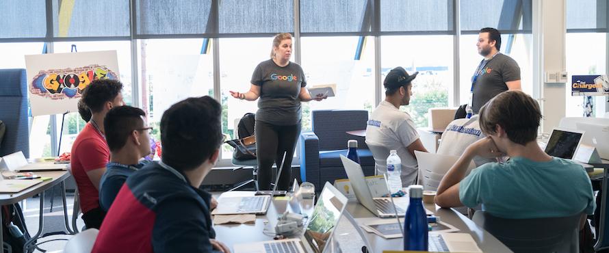 Photo of Northeastern professors wearing Google shirts and students in Northeastern shirts participating in a Computer Science Summer Institute Extension Program class at El Centro.