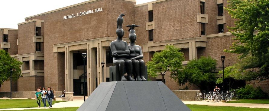 A statue is shown in front of a brick building on Northeastern's campus