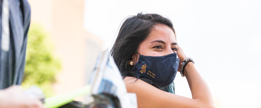 A student wearing a face mask looks off into the distance