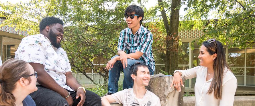 Four students sit outdoors on the Main Campus