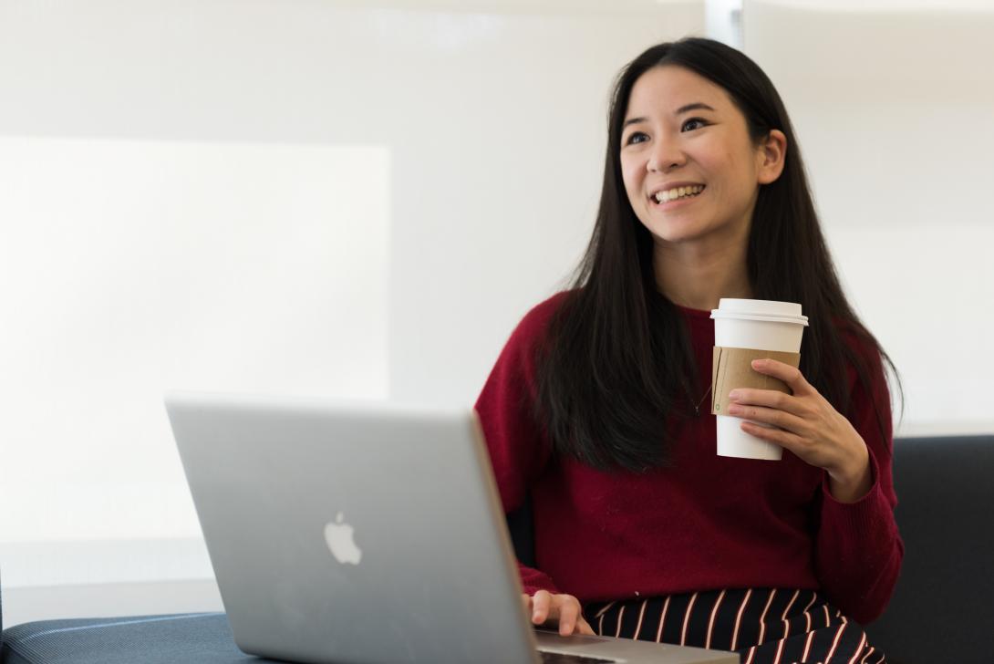 Student smiling while holding a cup of coffee