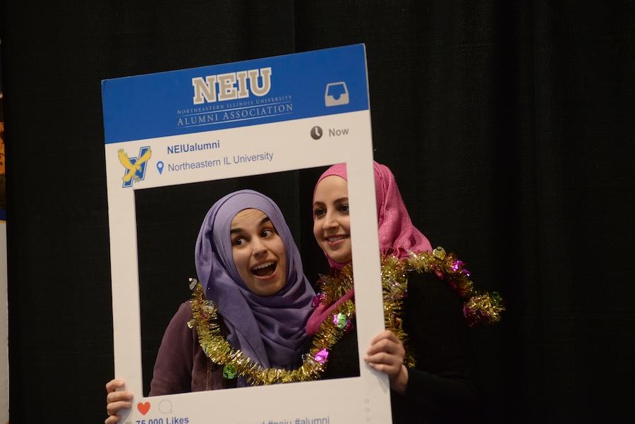 Two students posing with Alumni Affairs social media board