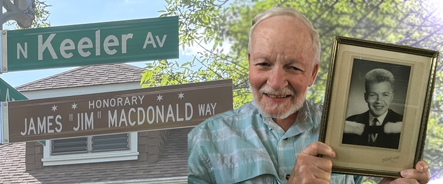 A composite photo. On the left of the frame, there are two street signs. One reads "N Keeler Ave," the other reads "Honorary James 'Jim' Macdonald Way." The right of the frame is a photo of James "Jim" Macdonald, smiling, wearing a blue button-down shirt and holding a photo of himself when he was younger (college portrait).