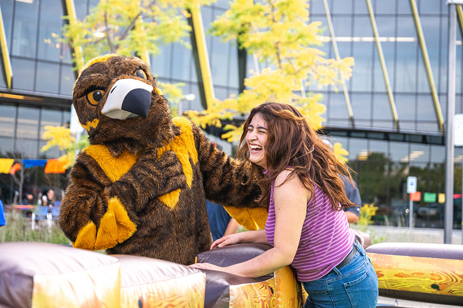 Woman laughing with Goldie the NEIU mascot
