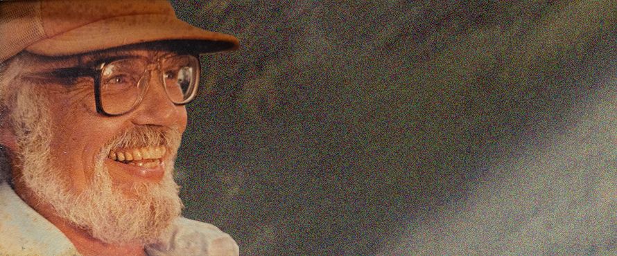 A headshot photo of William "Bill" Howenstine, Ph.D., smiling, wearing glasses and a baseball cap. 