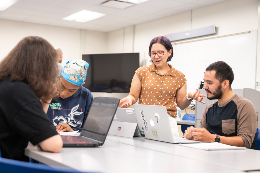 Professor explaining class content to a group of three students.