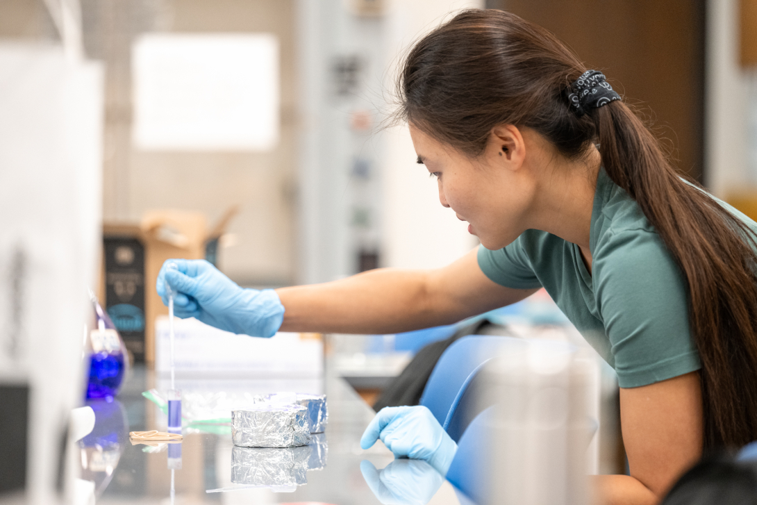 Student using a transfer pipette in a lab class.
