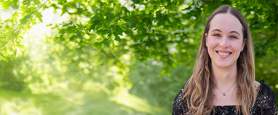 A photo of Northeastern Illinois University student Jennifer McDonnell, smiling, wearing a floral blouse, with green trees in the background.