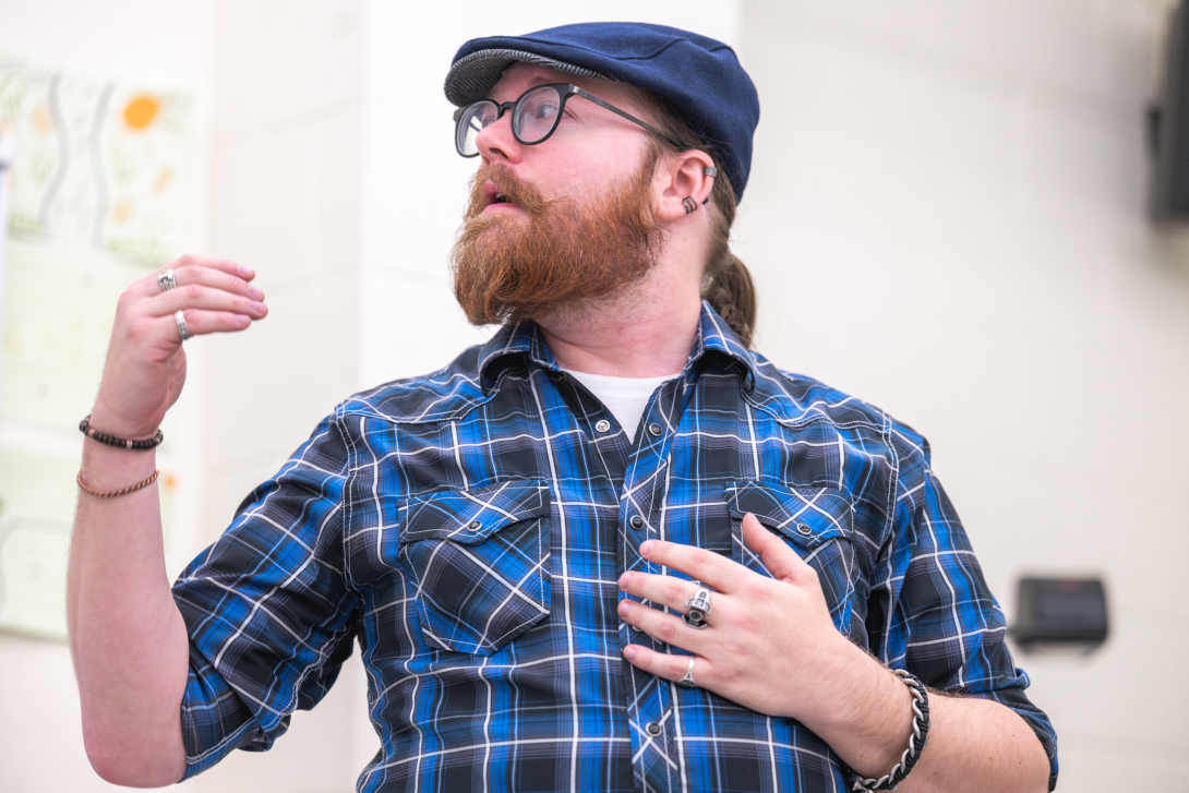 Image of student presenting wearing a blue plain shirt and hat.