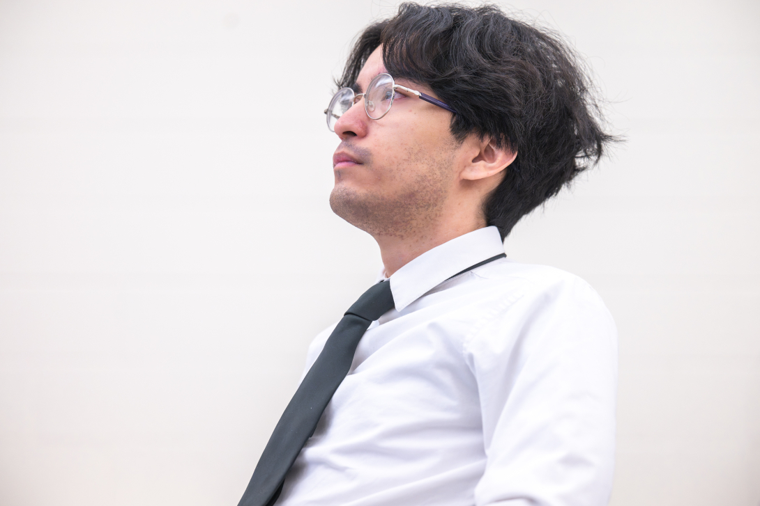 Photo from side of student wearing a white shirt and black tie.